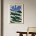 Kunstprint med blå blomst og spidse grønne blade i moderne nordisk indretning med træstol og lys væg