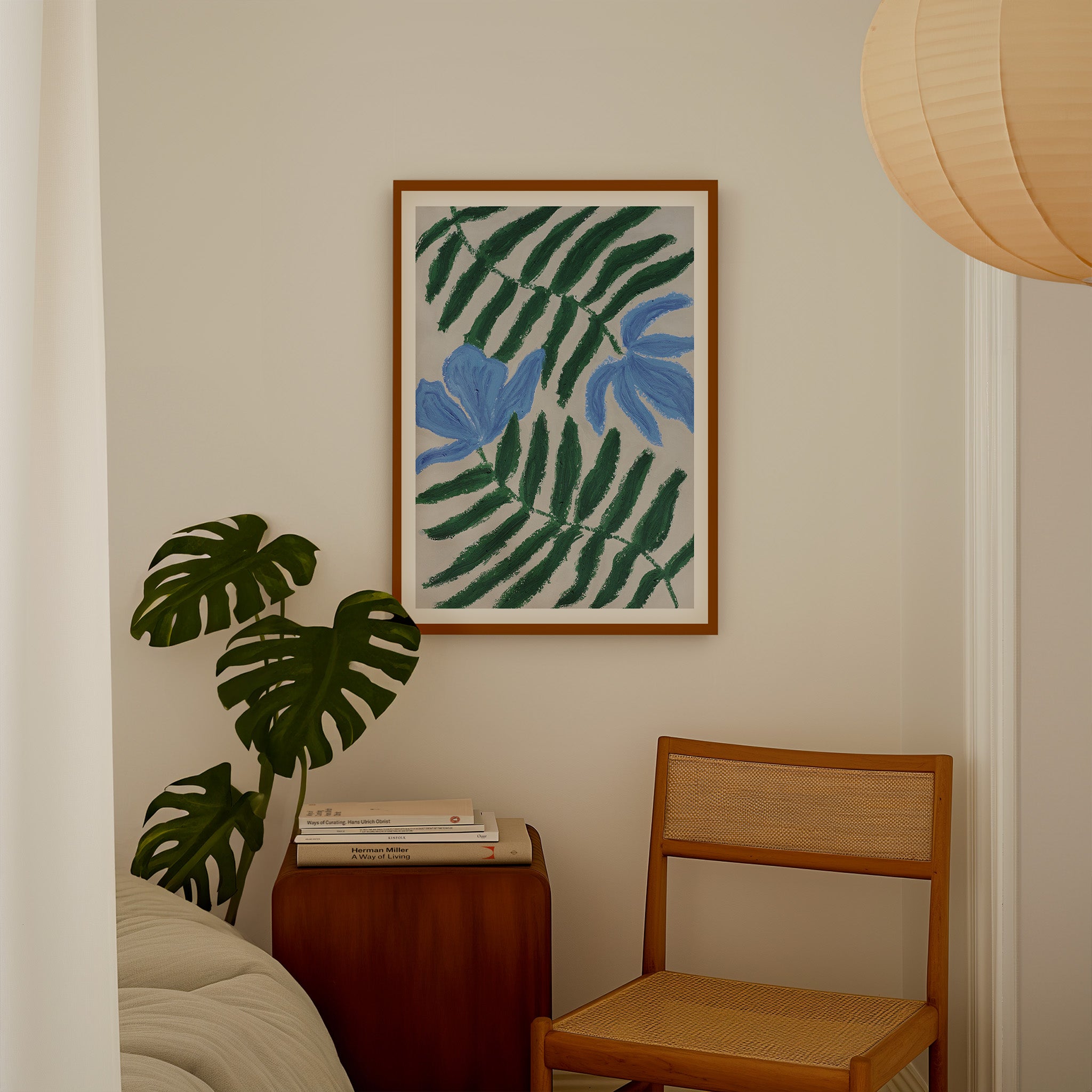 Kunstprint med blå blomster som del af nordisk indretning med fletstol i træ og en seng og monstera plante